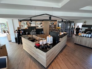 A modern kitchen area with a central island, bar area, and a person standing by the counter.