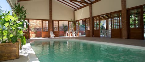 Una piscina techada, una piscina al aire libre, sombrillas