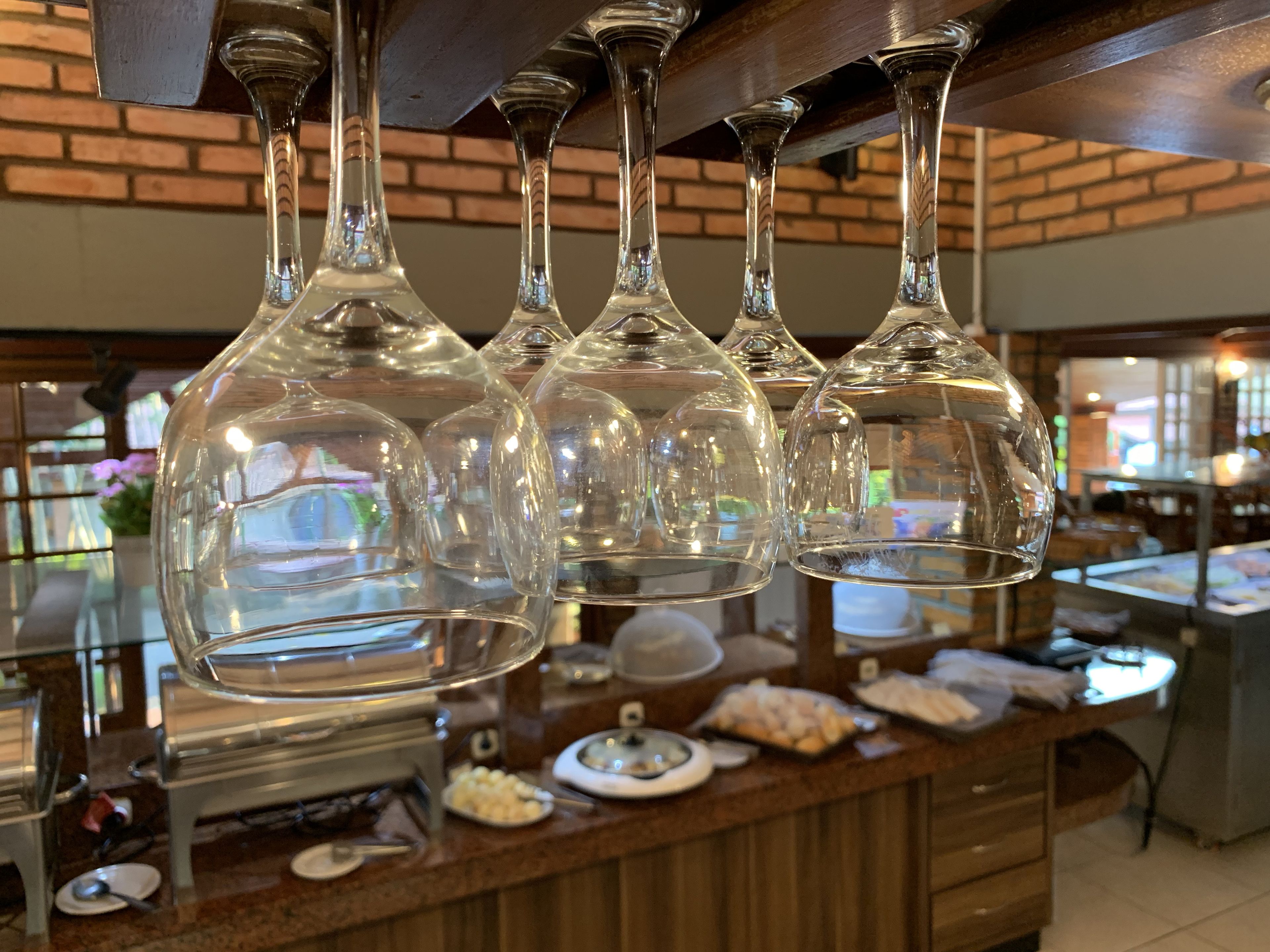 Zona de buffet con una barra que exhibe diferentes alimentos y una selección de copas de vino colgando en la parte superior.
