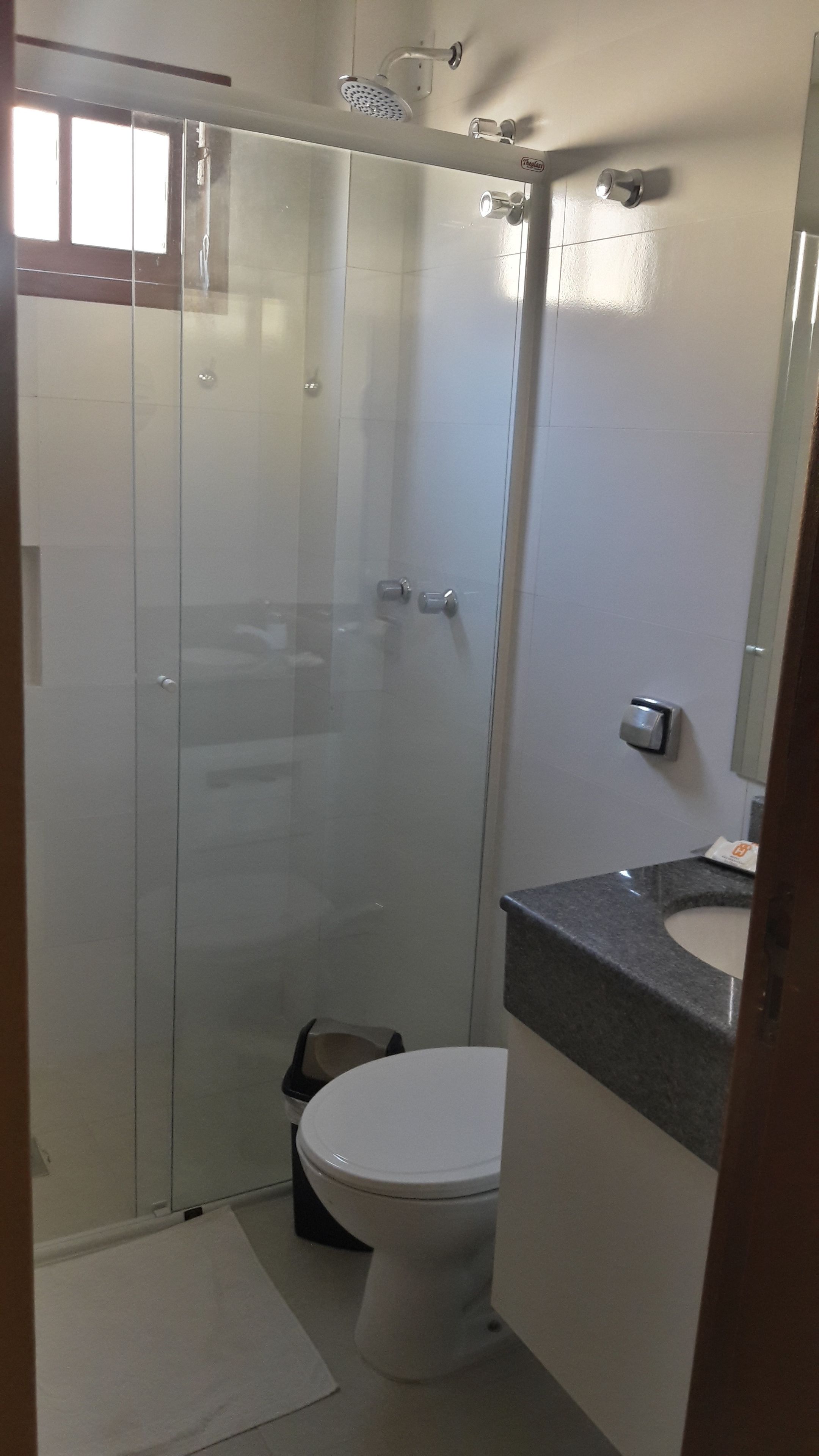 Un baño con cabina de ducha de vidrio, inodoro y lavamanos con encimera.