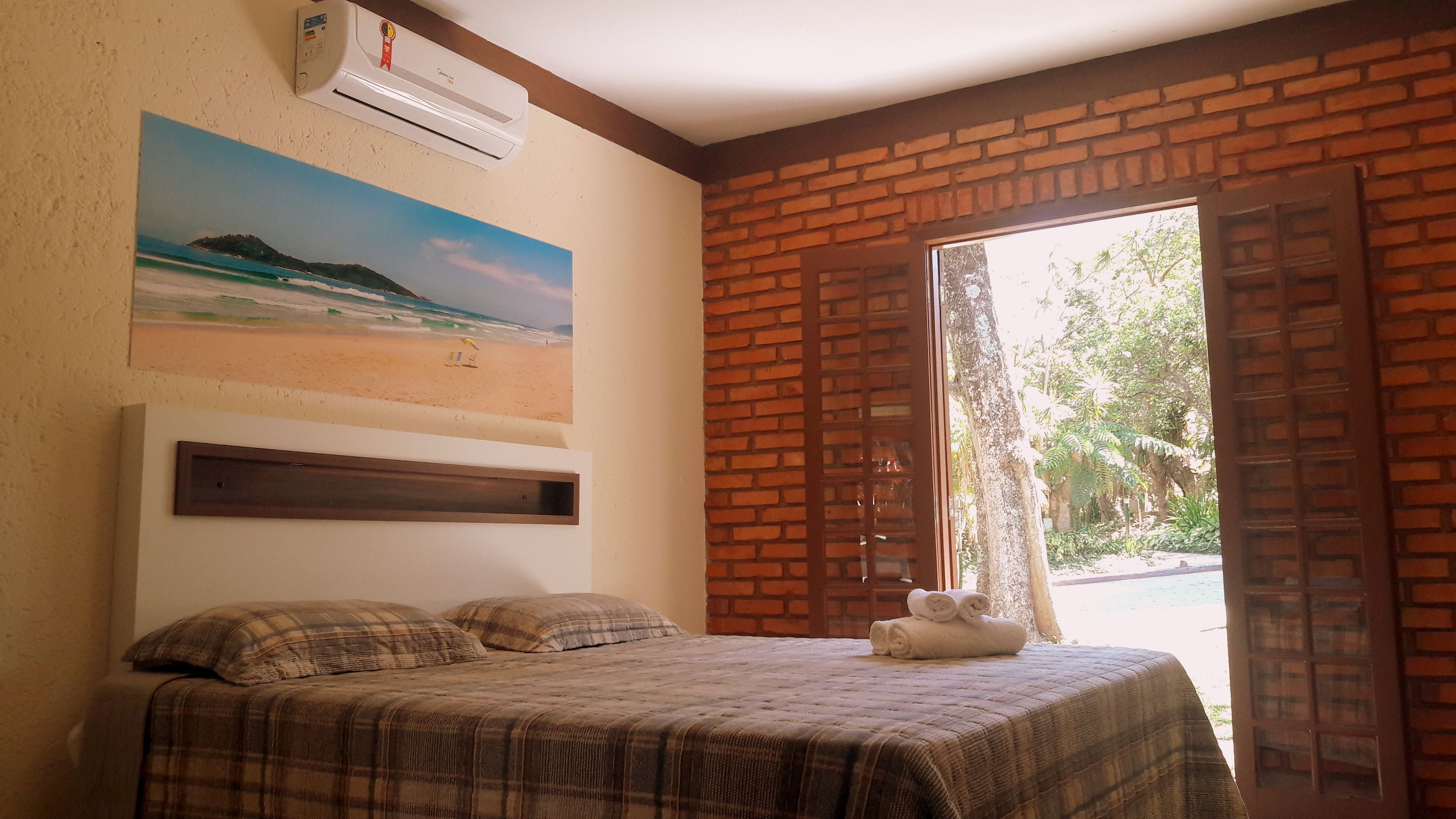Ein Schlafzimmer mit einem Bett, einem Strandbild und einer Ziegelwand.