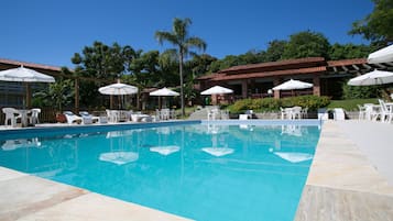 Una piscina techada, una piscina al aire libre, sombrillas