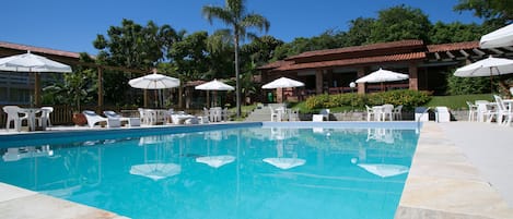 Una piscina techada, una piscina al aire libre, sombrillas