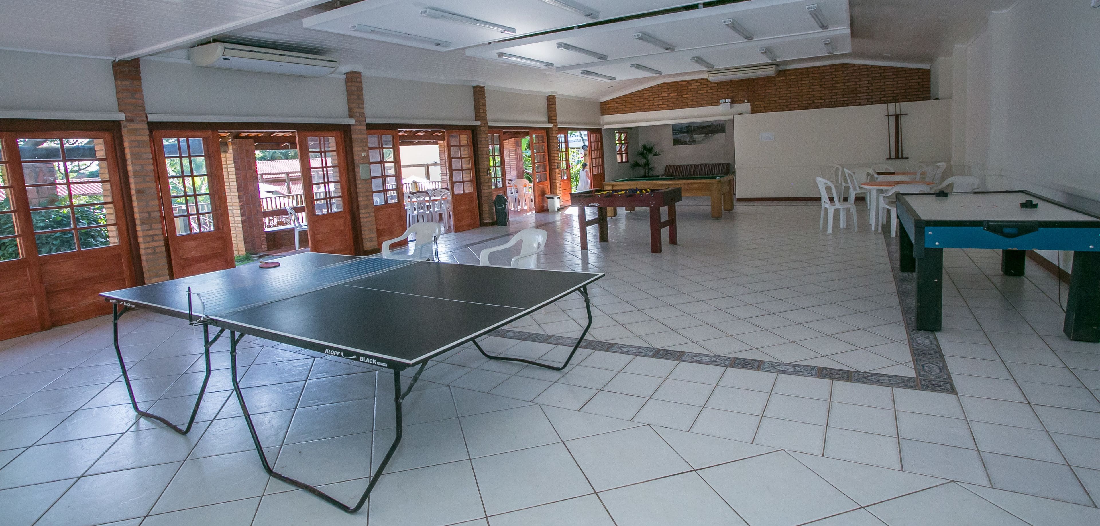 A spacious indoor area with a ping pong table, a pool table, and a billiards table.