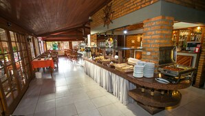 A buffet area with a brick wall, a wooden ceiling, and a tiled floor. - Hotel Sao Sebastiao Da Praia (Florianópolis)