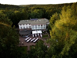 A large building with a circular central area, surrounded by a garden and multiple dining tables set up for an event.