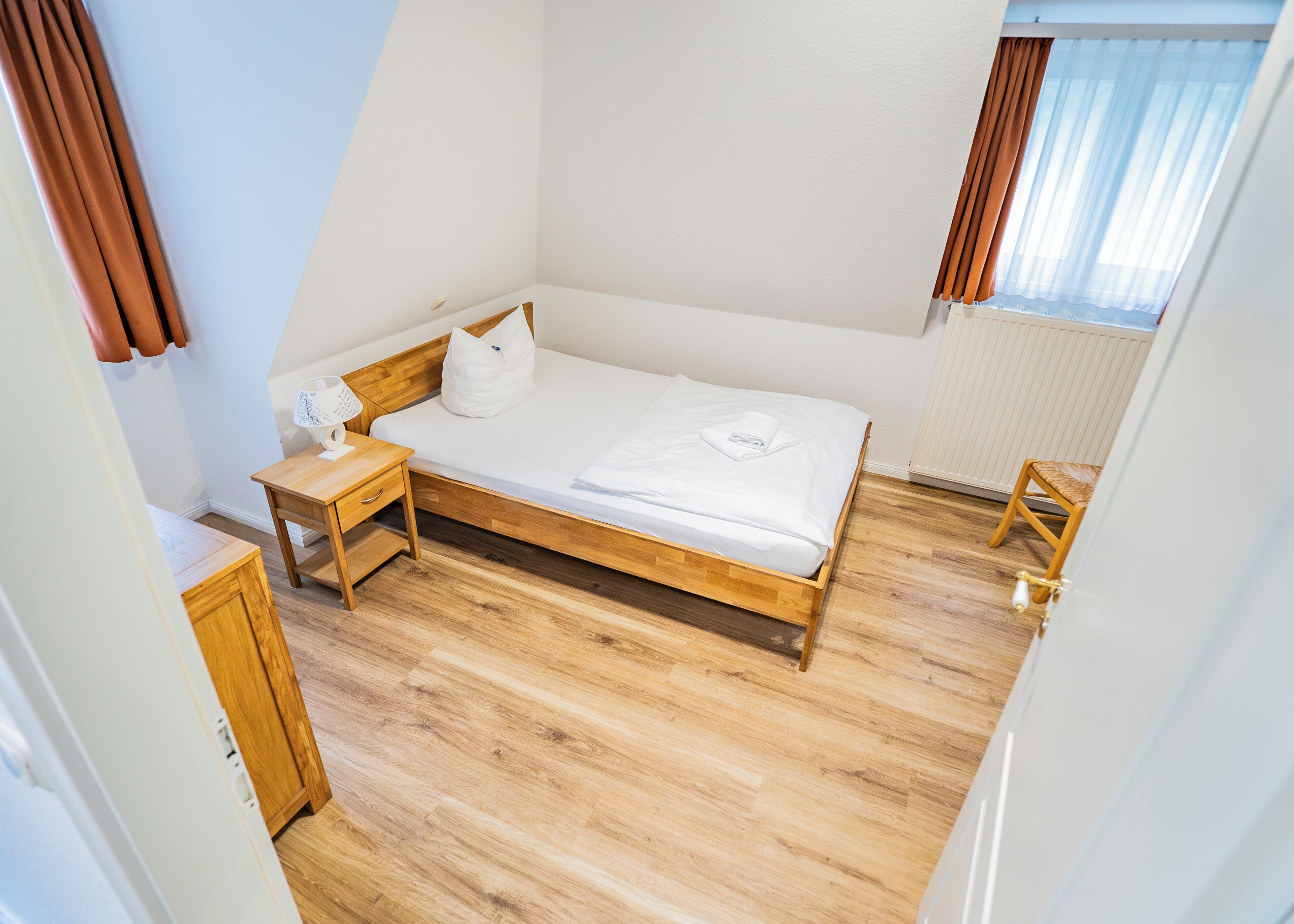 Un dormitorio con cama de madera, mesita de noche y silla.