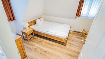 Un dormitorio con cama de madera, mesita de noche y silla.