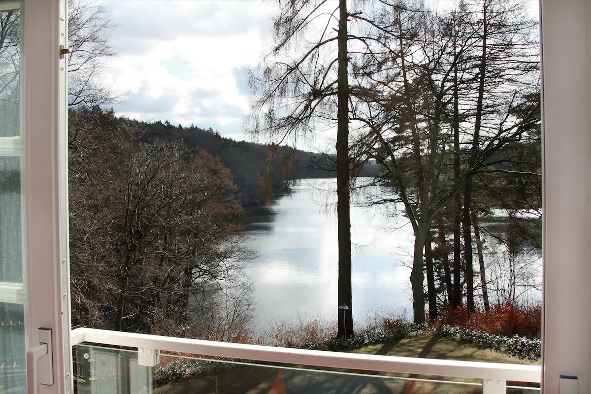 A lake surrounded by trees, viewed from a window with a white frame.