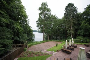 Un patio con mobiliario exterior, una terraza de madera y vistas a un lago.