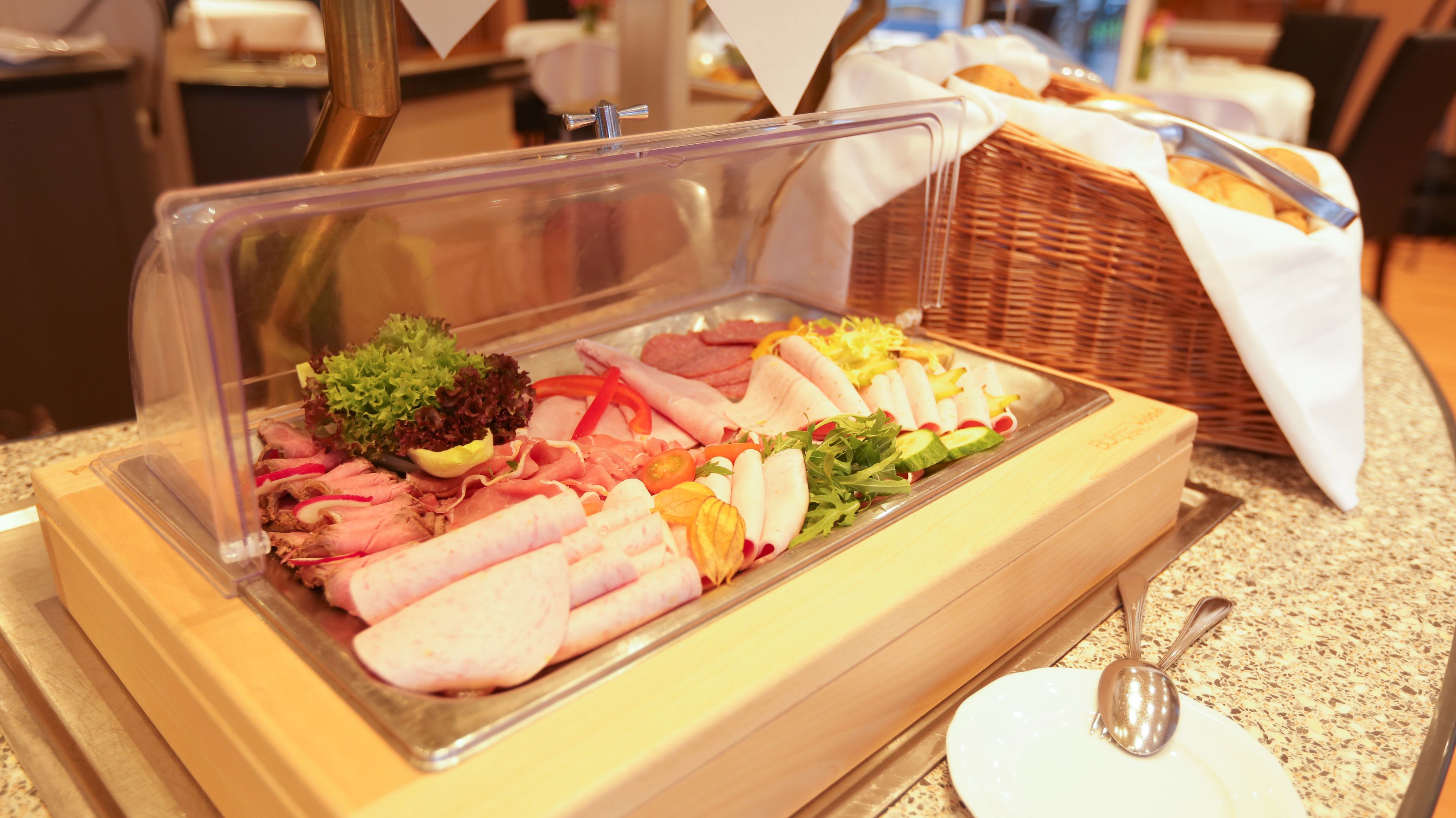A buffet with various meats, vegetables, and a salad.