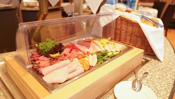 A buffet with various meats, vegetables, and a salad.