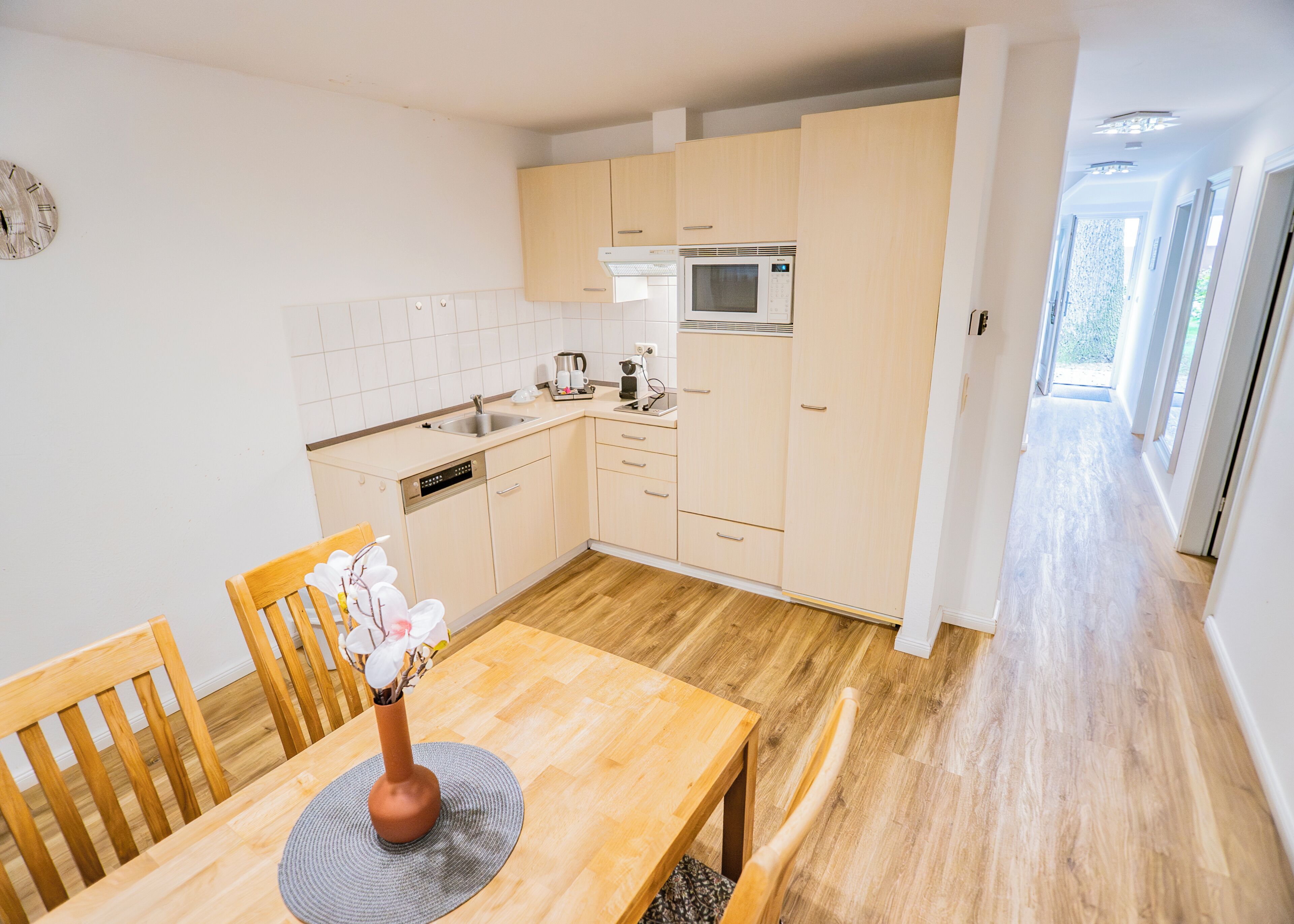 Una cocina moderna con armarios de madera, microondas integrado y una mesa de comedor con sillas.