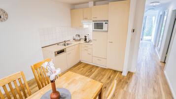 Una cocina moderna con armarios de madera, microondas integrado y una mesa de comedor con sillas.