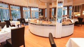 Un restaurante con un mostrador central de buffet, mesas redondas y sillas.