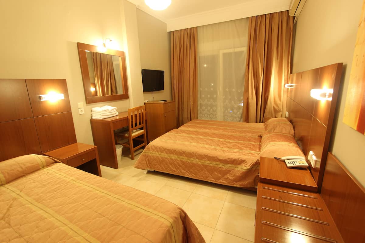 A hotel room with two beds, a desk, a chair, a TV, and a telephone.