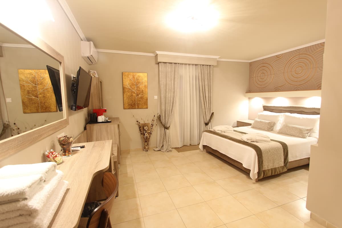 A hotel room with a bed, a desk with a chair, a large mirror, and artwork on the walls.