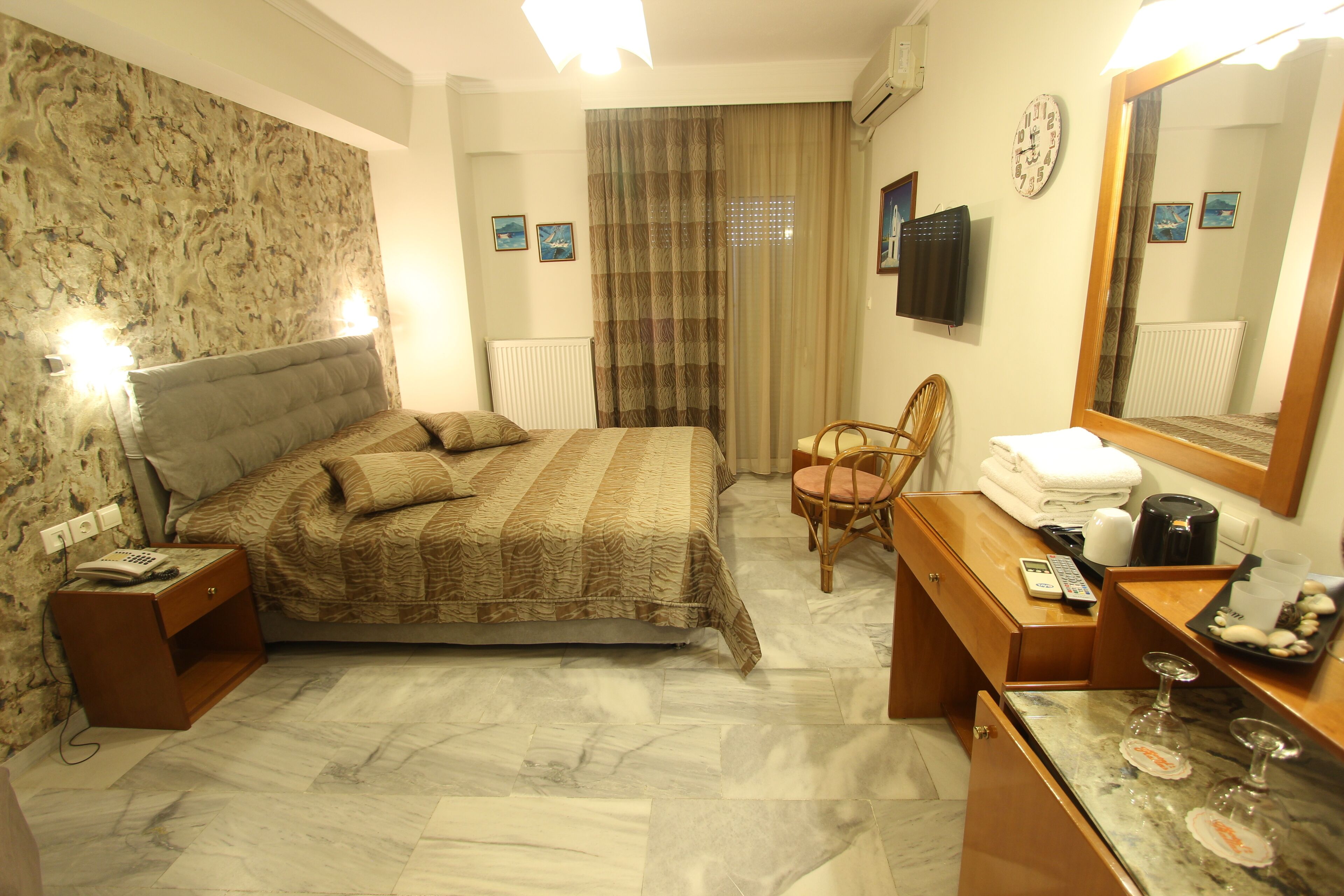 A hotel room with a bed, bedside table, chair, dresser, and a mirror.