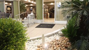 A hotel lobby with a reception desk, a 'Welcome' mat, a palm tree, and a fountain. - Hotel Mallas (Nea Propontida)