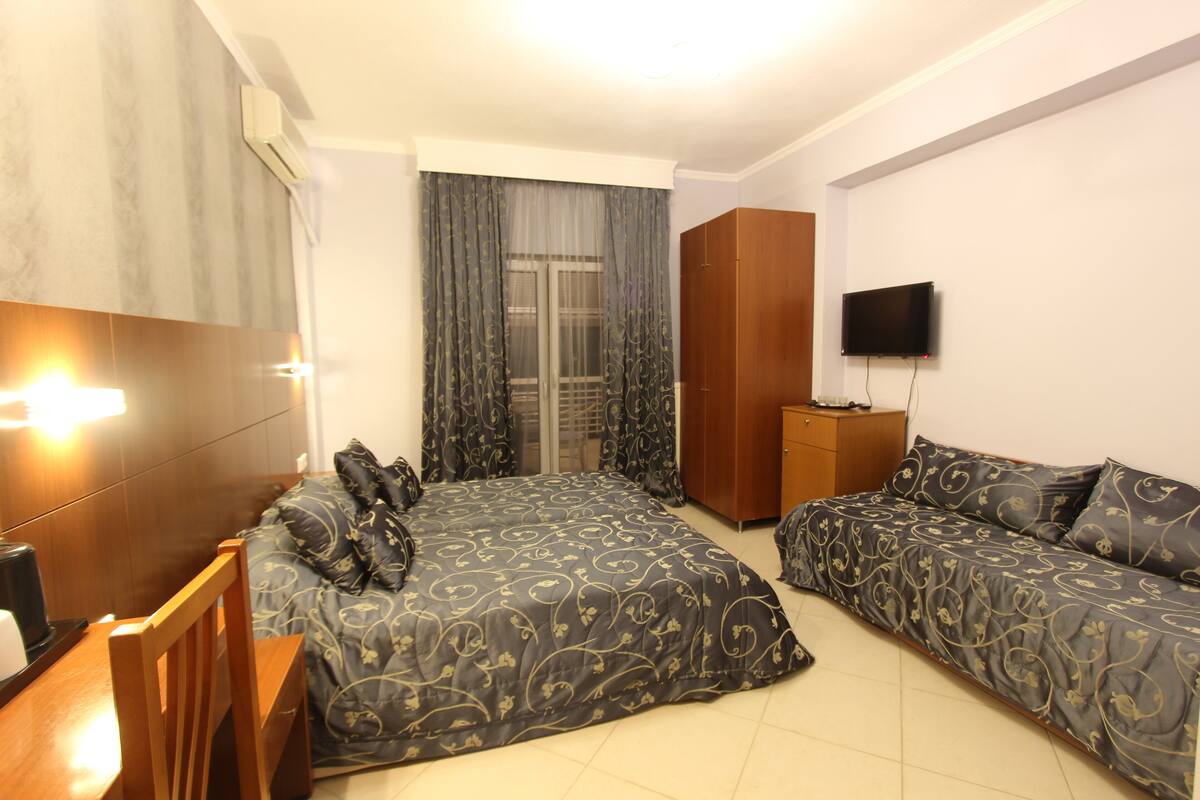 A hotel room with a bed, a desk, a chair, a wardrobe, and a TV.