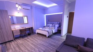 A modern bedroom with a bed, a desk, a chair, a sofa, and a large mirror. - Hotel Mallas (Nea Propontida)