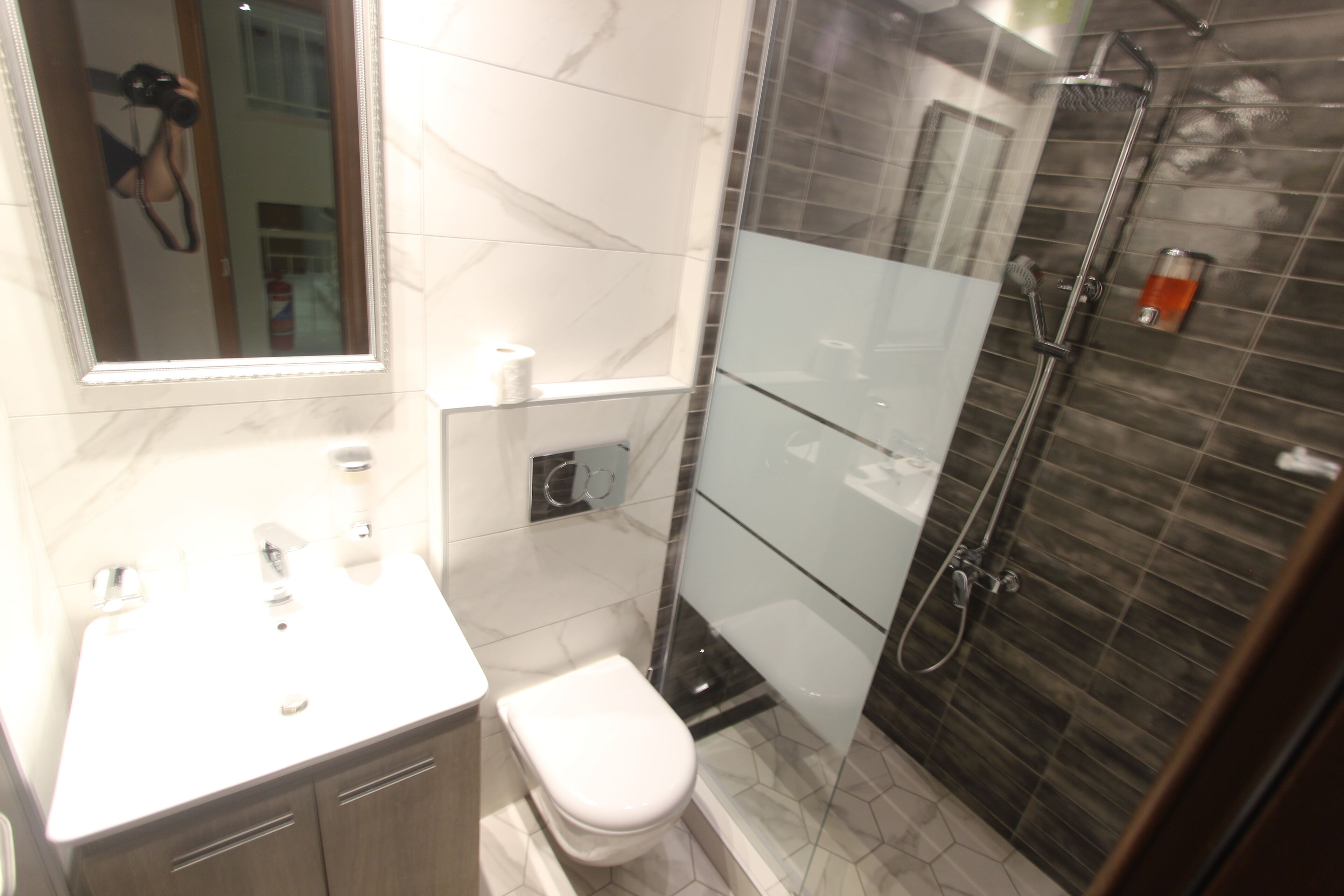 Un baño moderno con cabina de ducha de vidrio, inodoro blanco y tocador con espejo.