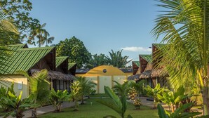 Un resort con bungalows de techo de paja, un edificio central y exuberante vegetación tropical.