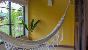 Una hamaca en una habitación con paredes amarillas y una ventana que da a un jardín.