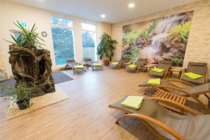 A spa room with wooden chairs, a large waterfall mural, and potted plants. - Rosenhotel (Sangerhausen)