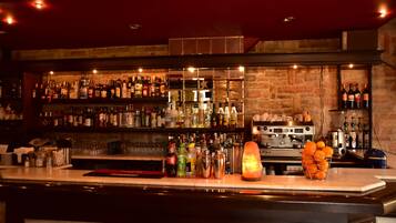 A bar area with shelves of liquor bottles, a cocktail shaker, and a fruit basket.