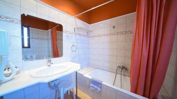 Un baño con lavamanos, espejo y ducha blancos.