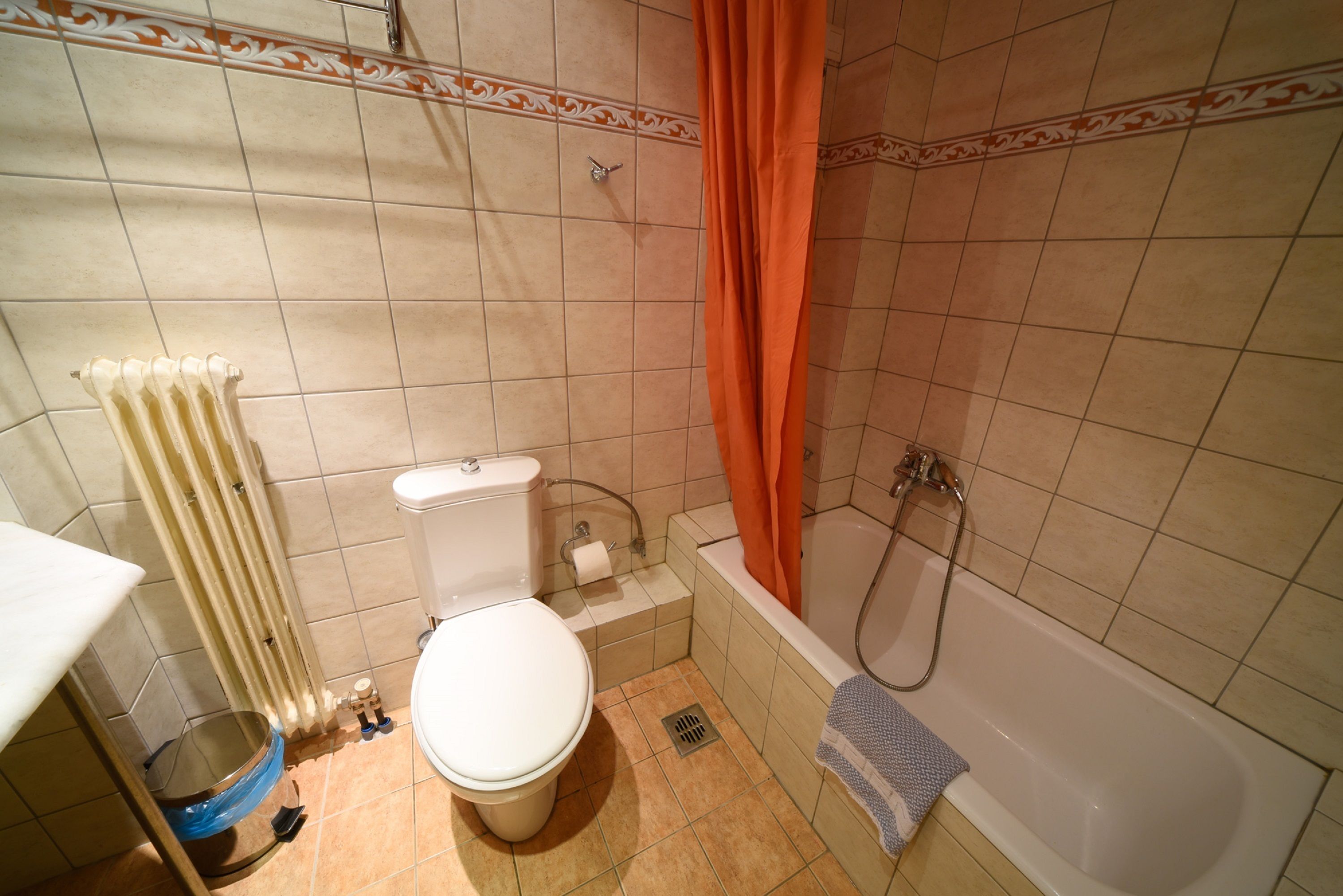 Ein kleines Badezimmer mit Toilette, Badewanne, Dusche und einem blauen Waschbecken.