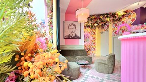 Een kamer met een zwart-wit geruite vloer, een kroonluchter, een bloemenbehang en een barhoek.