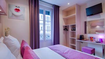 A hotel room with a bed, a desk, a TV, and a window with curtains.