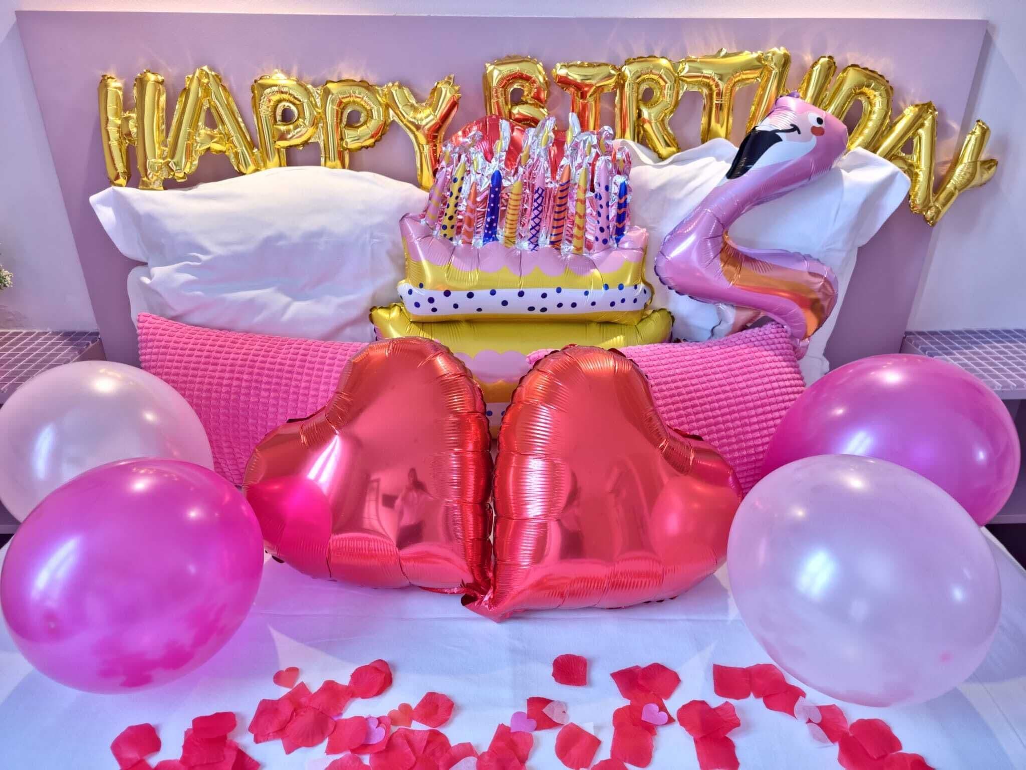 Decoración de fiesta de cumpleaños con globos, un pastel y una figura de flamenco.