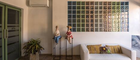 Un espace d’accueil avec un canapé blanc, une porte verte portant l’inscription « SPA », et un mur orné d’une grille de petites fenêtres.