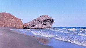 A beach with a large rock formation and waves crashing onto the shore. - Hotel de Naturaleza Rodalquilar Spa Cabo de Gata (Nijar)