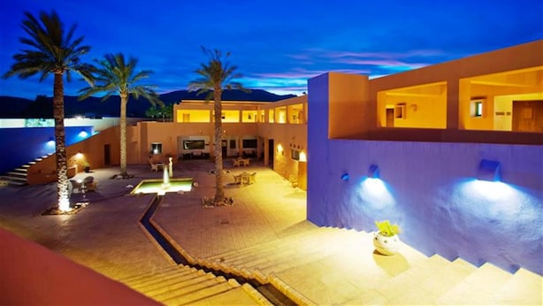 A modern hotel with a courtyard, palm trees, and a staircase leading to the upper levels. - Hotel de Naturaleza Rodalquilar Spa Cabo de Gata (Nijar)