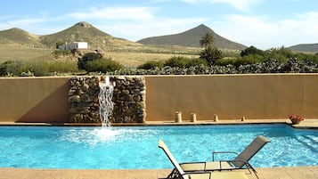 Una piscina al aire libre, tumbonas