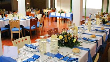 Un salón de banquetes con varias mesas dispuestas para comer, con manteles azules y platos blancos.