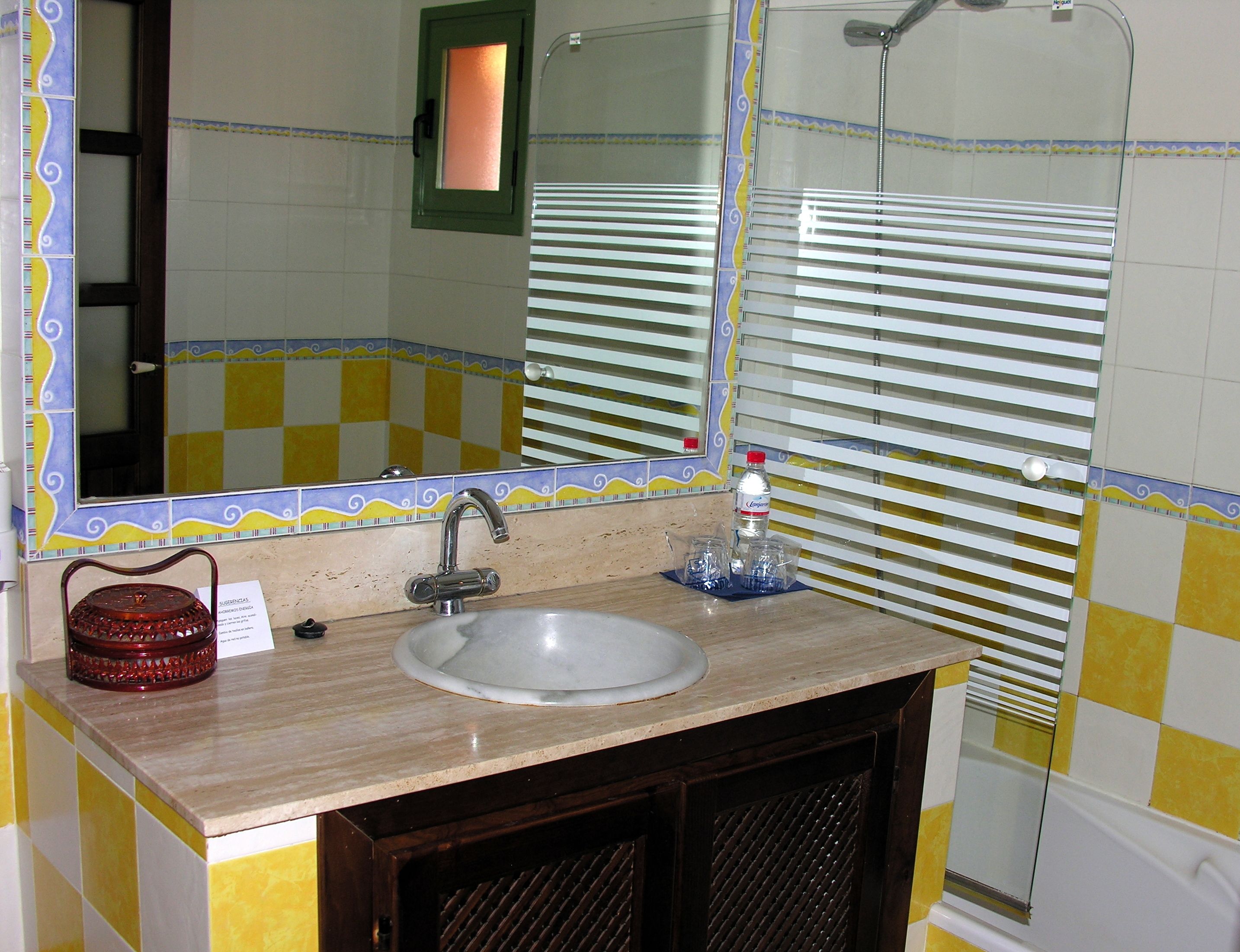 Een badkamer met een wastafel, spiegel en douche.