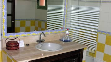 A bathroom with a sink, mirror, and shower.