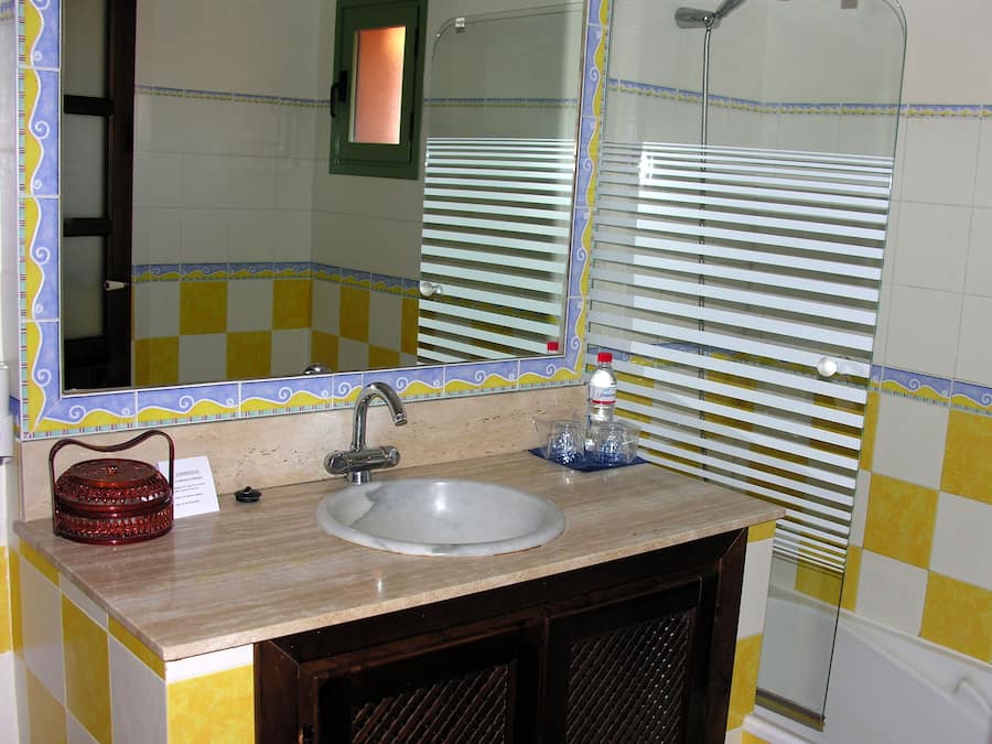 A bathroom with a sink, mirror, and shower.