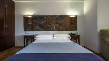 Habitación de hotel con una cama grande, un armario de madera, una mesita de noche con lámpara y una obra de arte colgada en la pared.