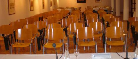 A conference room with rows of chairs, a white table with a microphone, and a nameplate.