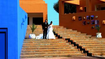 A couple on a staircase with a blue building on the left and an orange building on the right.