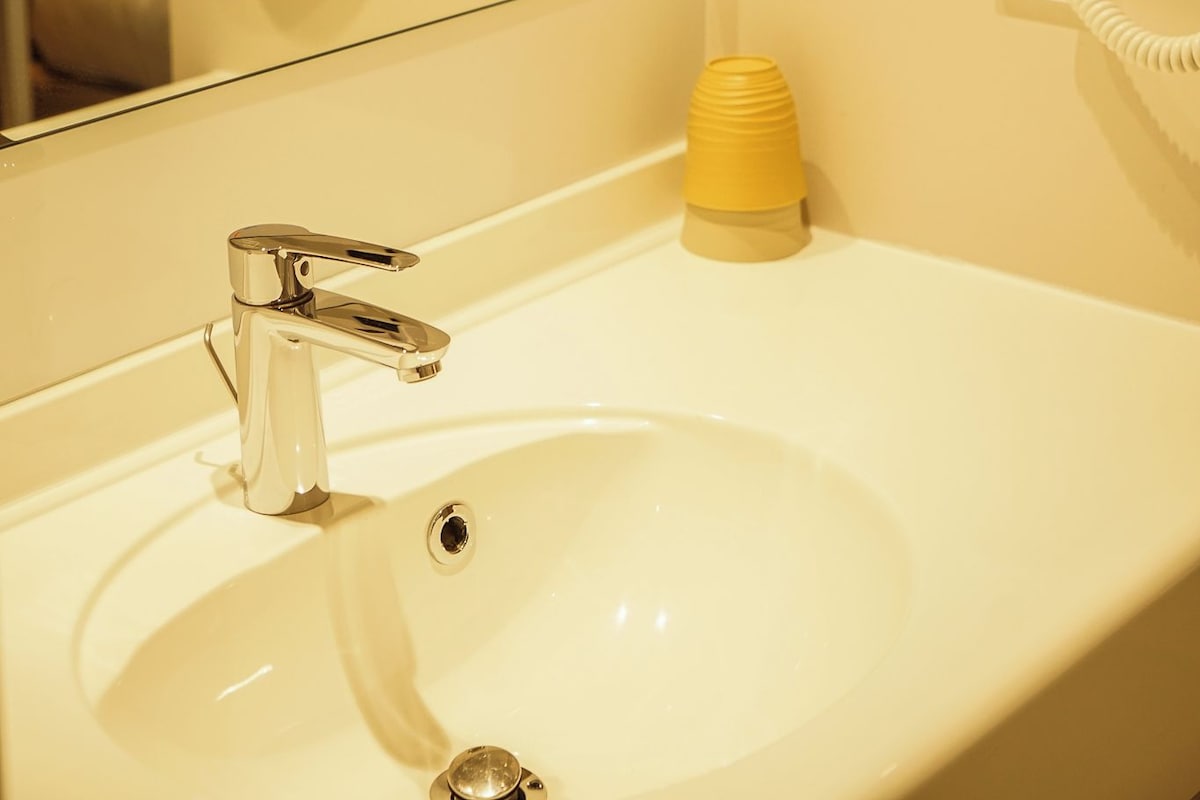 A bathroom with a sink, mirror, and two hair dryers mounted on the wall.