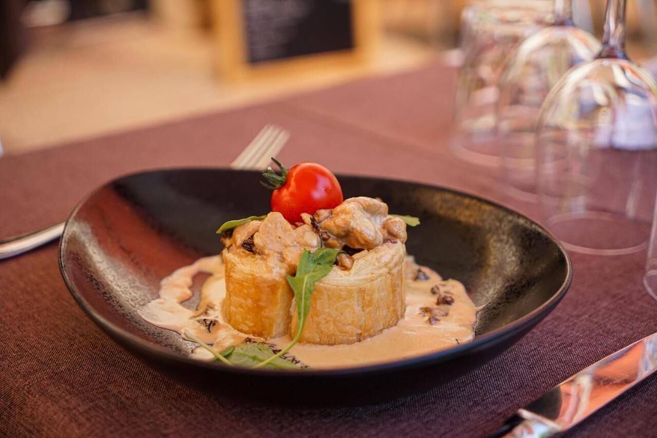 A plate of food with a fork and a glass of water on a table.