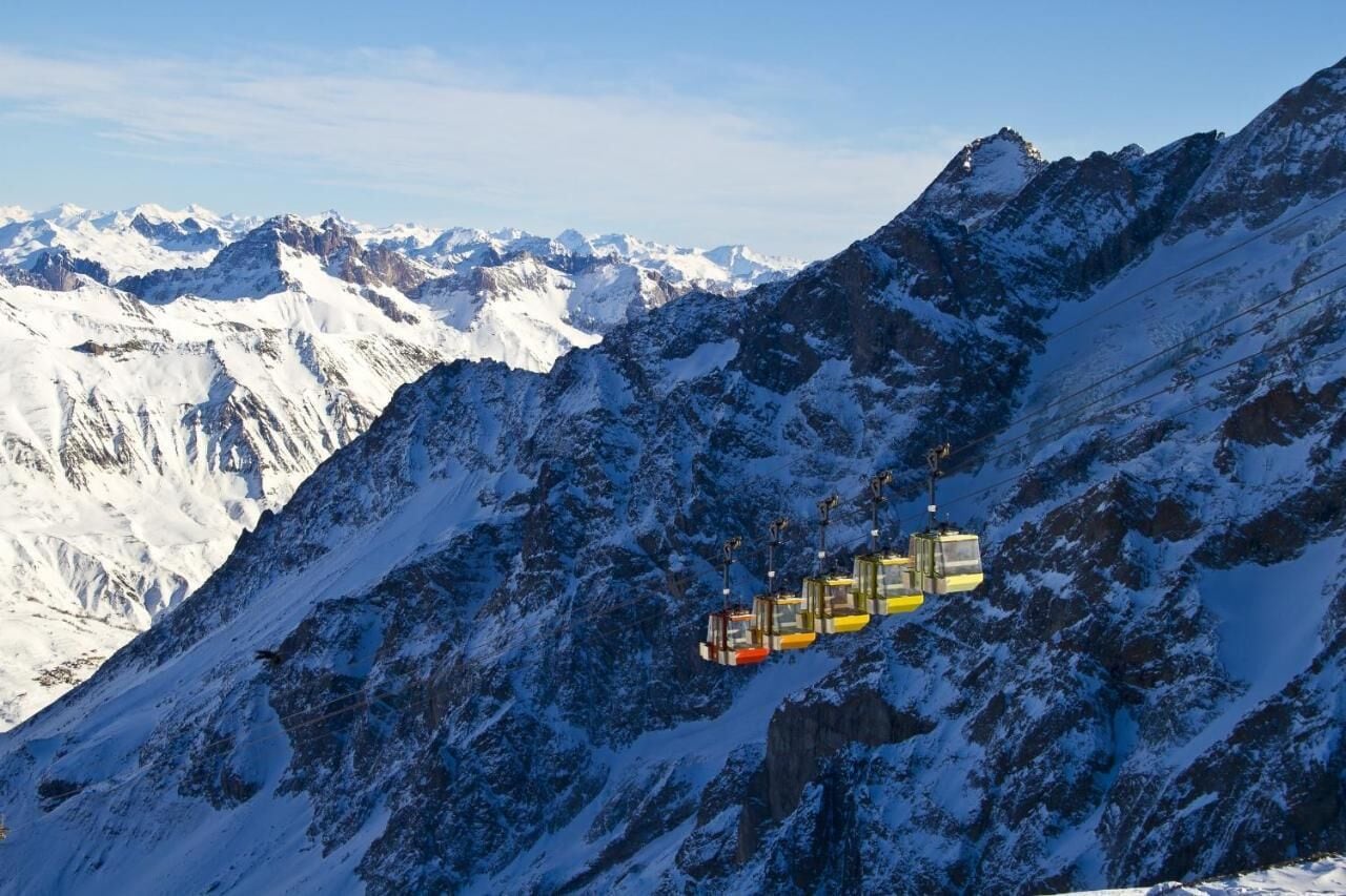 Een kabelbaan in een bergachtig gebied met met sneeuw bedekte toppen.