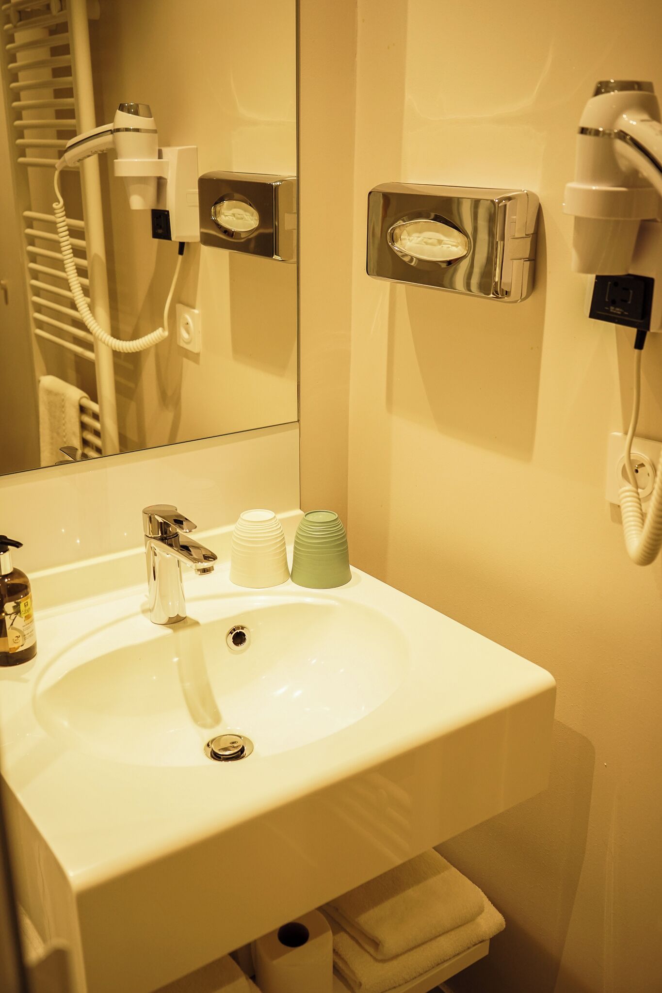 A bathroom with a white sink, a mirror, a hairdryer, and a towel rack.